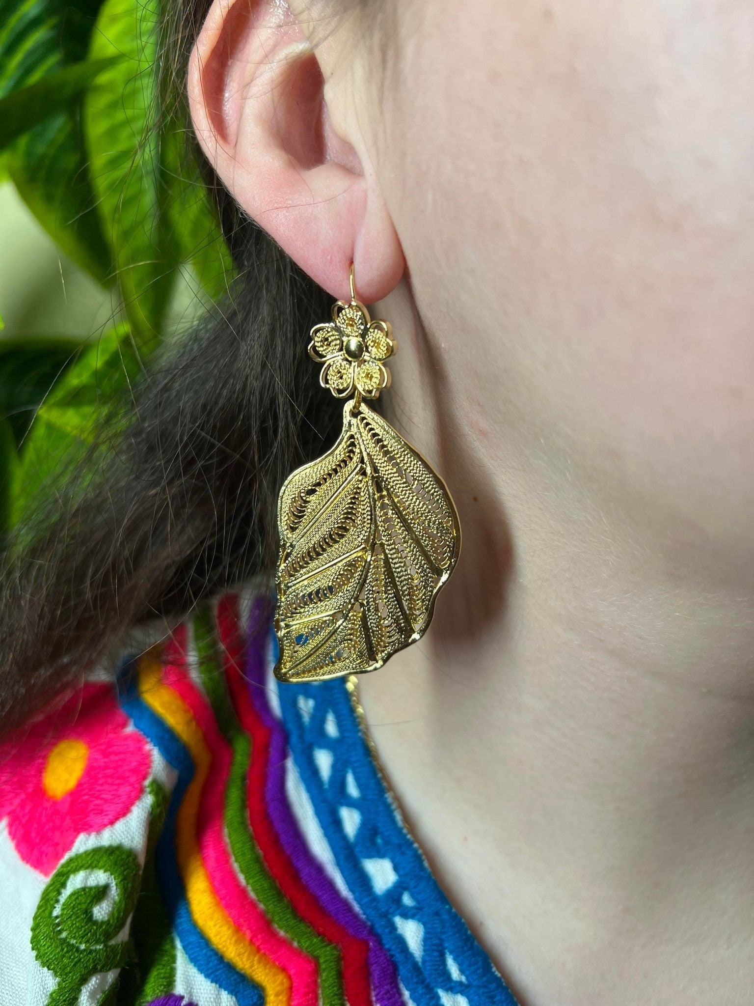 Gold Filigree Leaf inspired earrings on model's earlobe.