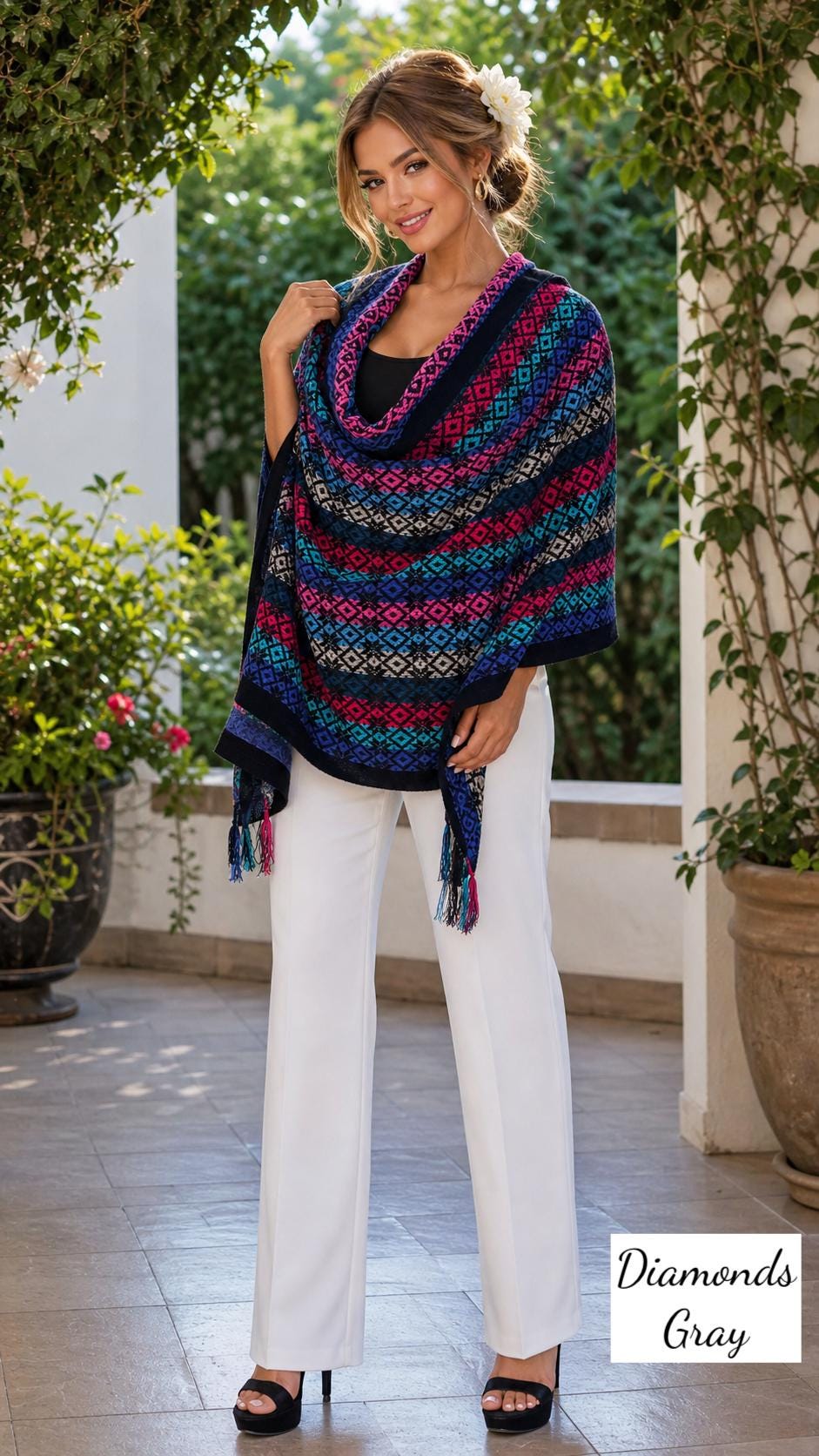 Image of May include: A colorful shawl with a geometric pattern in shades of blue, pink, and teal. The shawl has a black border and tassels. The model is wearing white pants. The text "Diamonds Gray" is in the bottom right corner.